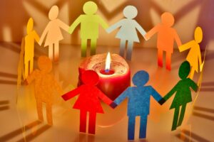 multicolored paper people around a candle